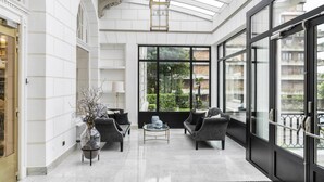Un vestíbulo amplio con techos altos, ventanas grandes y mobiliario moderno.