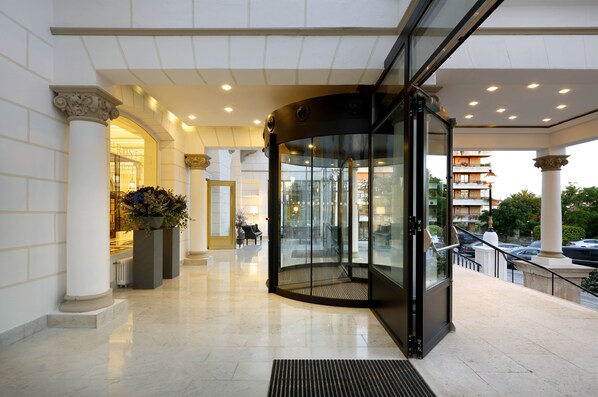 Un moderno vestíbulo de hotel con puerta giratoria, suelo de m ármol y vistas a la calle.