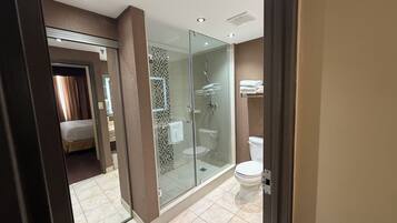 Un baño moderno con ducha envuelta en vidrio, inodoro y toallero a la vista.
