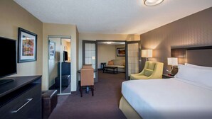 Ein Hotelzimmer mit einem Bett, einem Schreibtisch, einem Sessel, einem Fernseher und einer Couch.