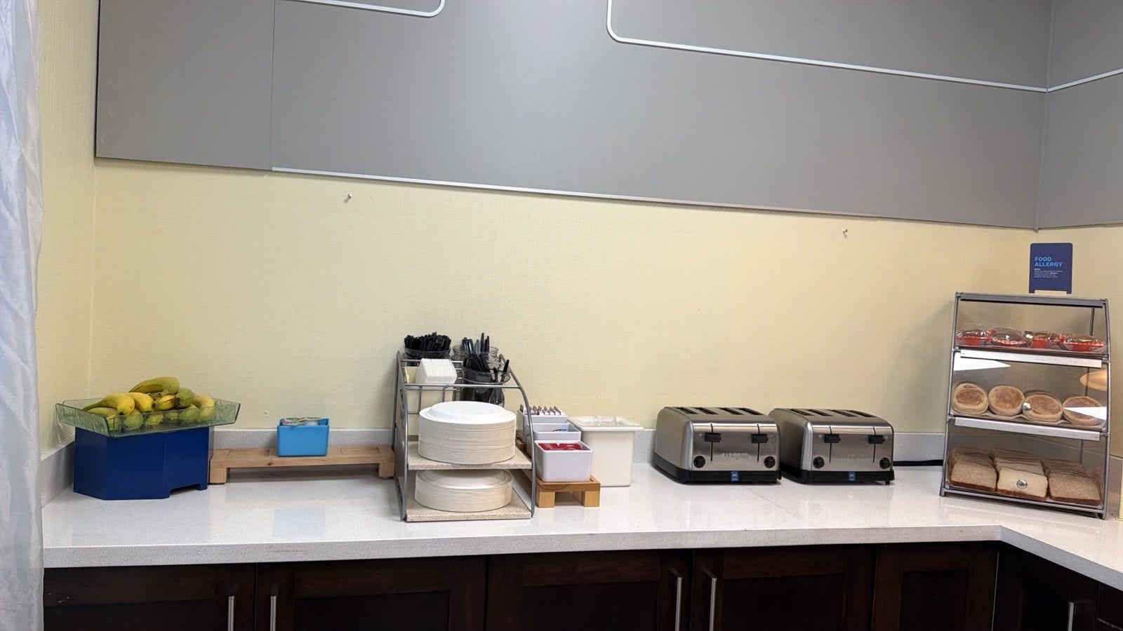 A breakfast bar with a fruit bowl, a dish rack, a toaster, and a bread display.