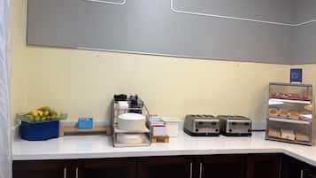 A breakfast bar with a fruit bowl, a dish rack, a toaster, and a bread display.