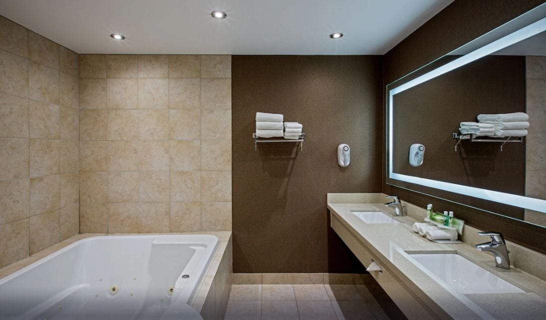 A modern bathroom with a large bathtub, two sinks, and a mirror.