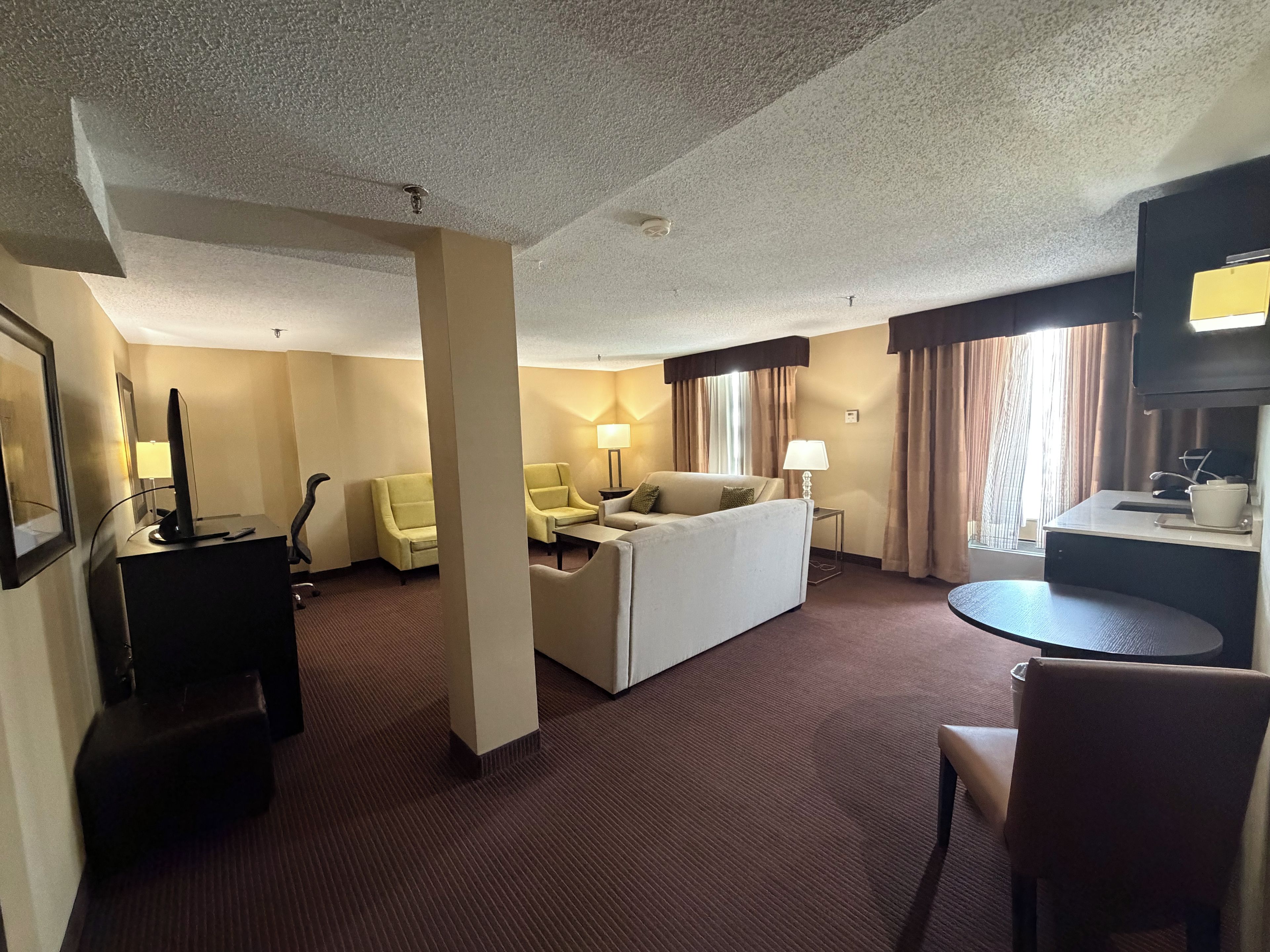 Una habitación de hotel con cama, escritorio, sillón, sofá y televisor.