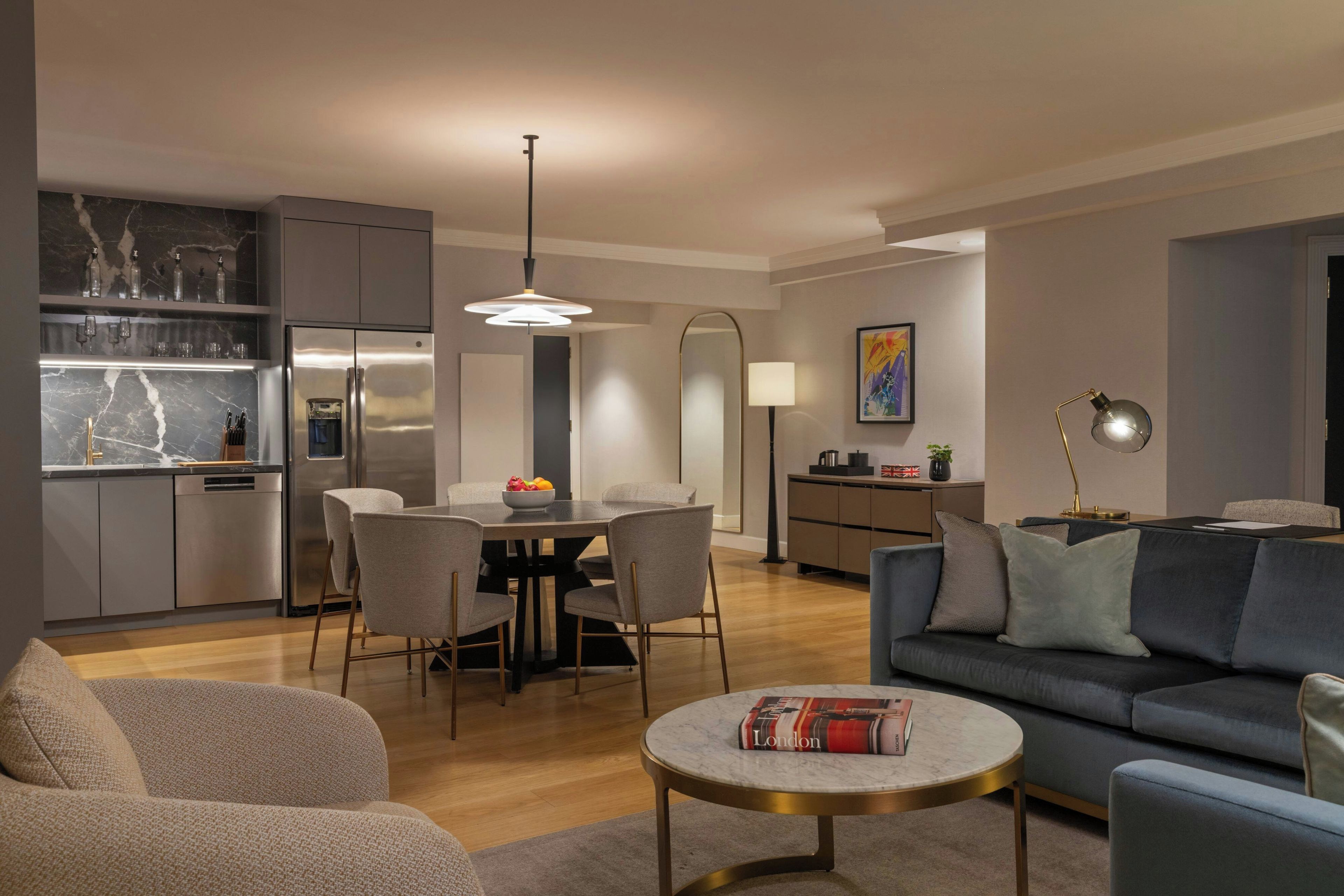 A modern living room with a sofa, a coffee table, and a dining area with chairs and a table.