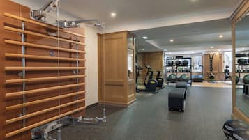 A gym with exercise equipment, a mirror, and a wooden rack.
