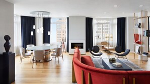 A modern living room with a fireplace, a dining area, and a red sofa. - The London, a Luxury Collection Hotel, New York City (New York)