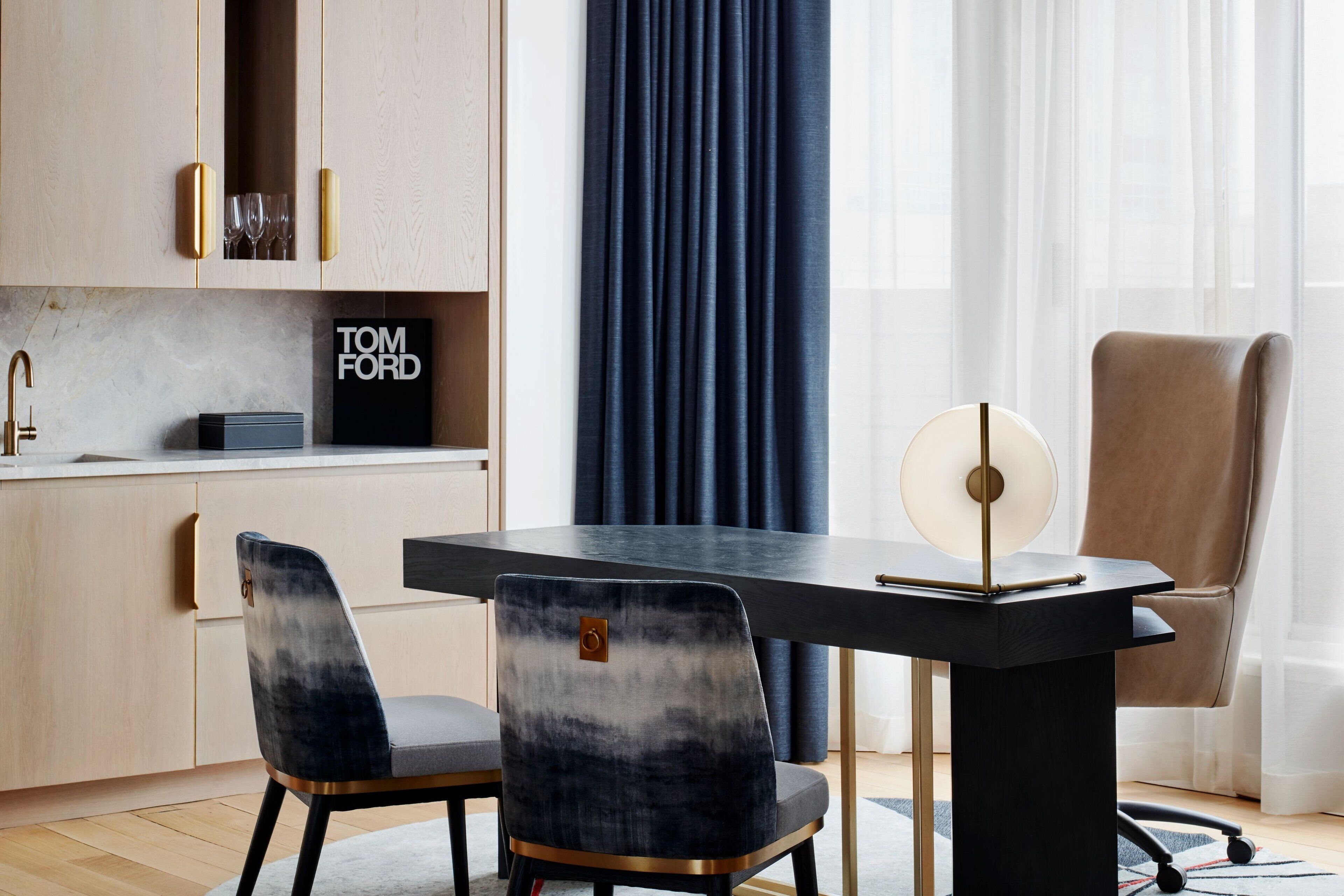 A modern dining area with a black table, two chairs, and a decorative lamp.