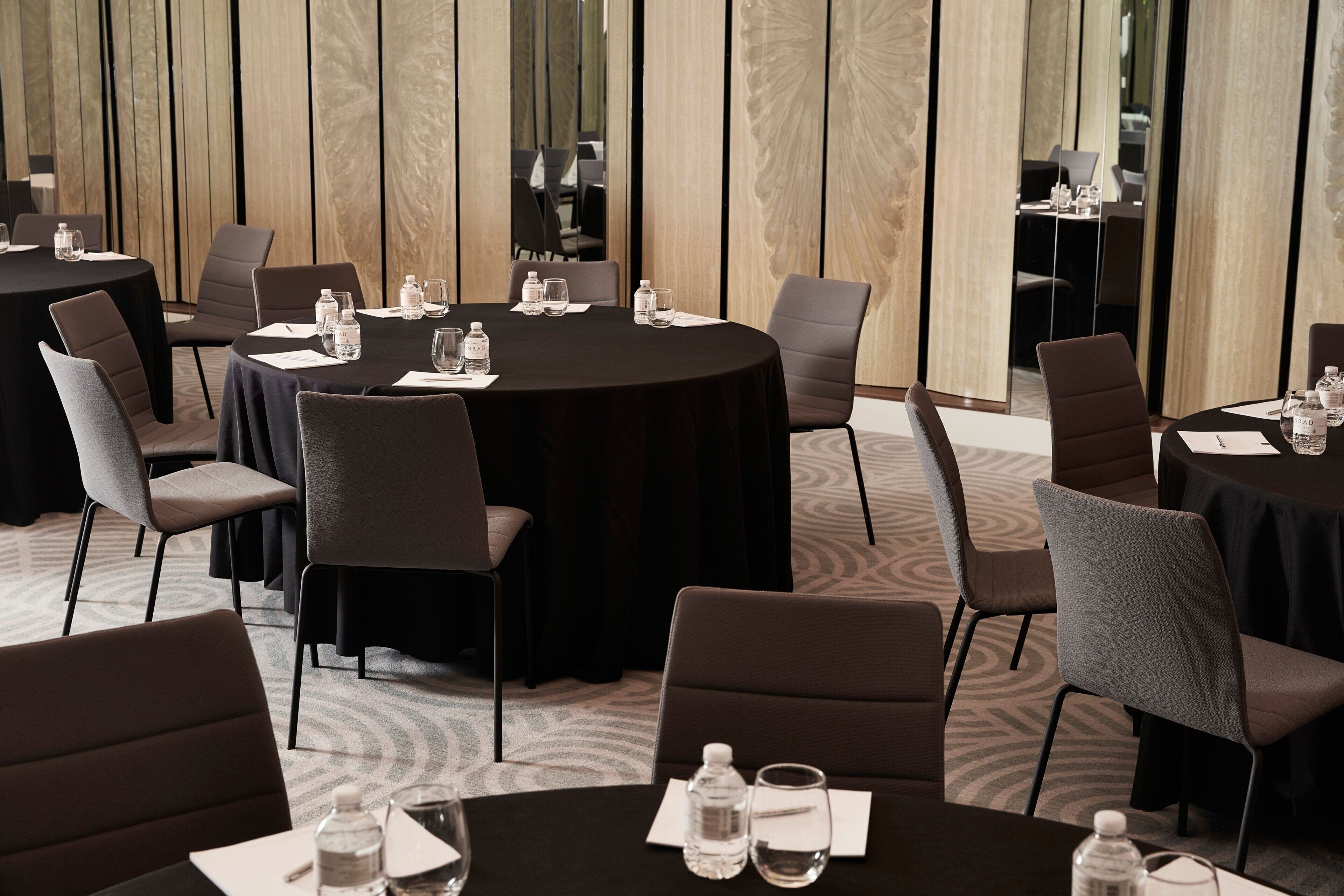 A conference room with round tables, chairs, and water bottles.