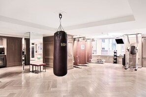A spacious gym with a punching bag, exercise equipment, and a bench. - The London, a Luxury Collection Hotel, New York City (New York)