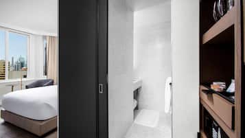 Quarto de hotel com cama, guarda-roupa, casa de banho com chuveiro e vista para a cidade.