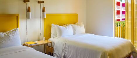 A hotel room with two beds, a nightstand, and a window with yellow curtains.