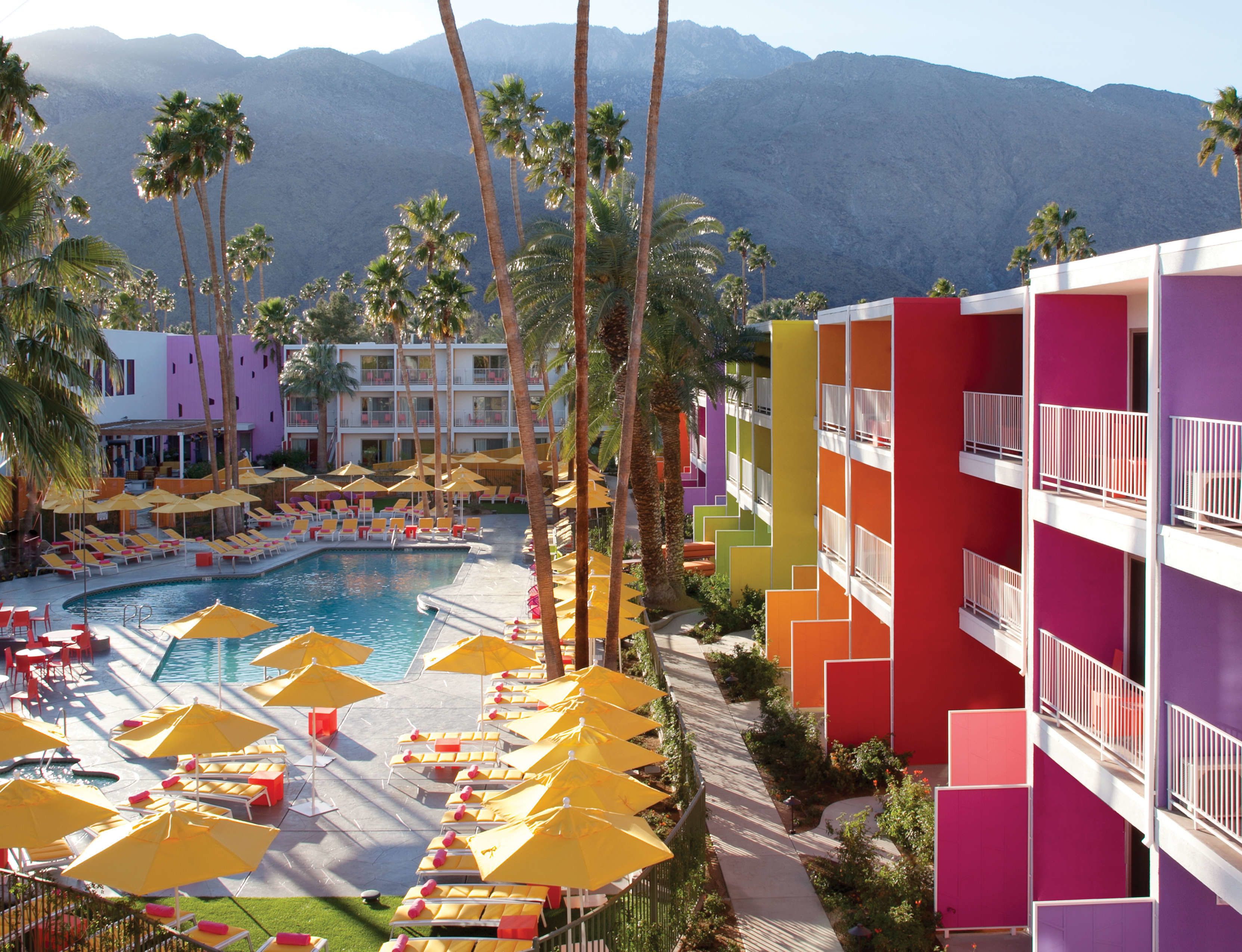 A hotel with a pool area, multiple floors, and a mountain backdrop.