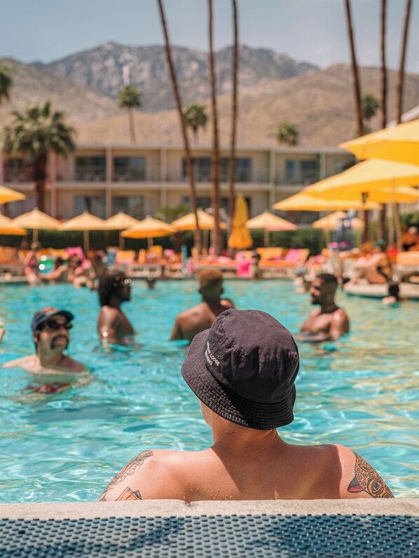 Una piscina al aire libre, camas de piscina con cargo, sombrillas