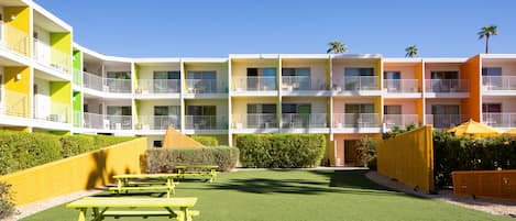 A multi-story hotel with balconies, a green lawn, and picnic tables.