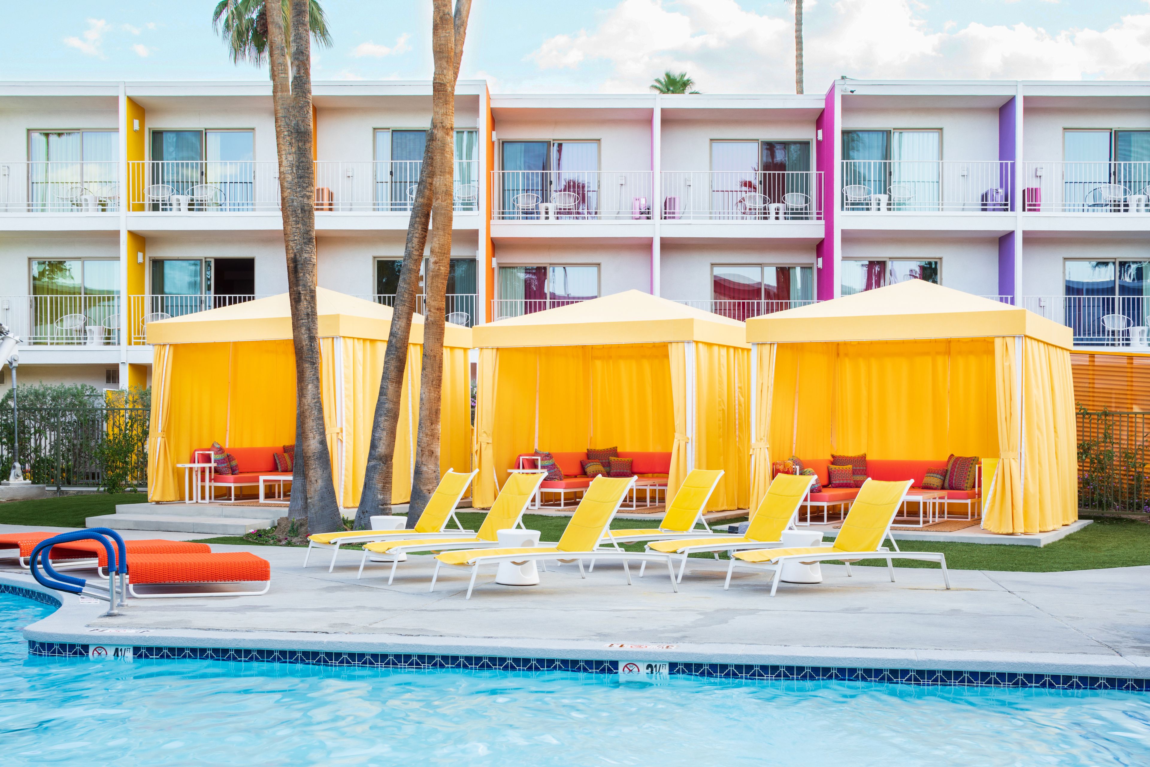 A hotel with a pool area, yellow canopies, and lounge chairs.
