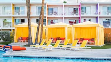 Un hotel con piscina, toldos amarillos y sillones de descanso.