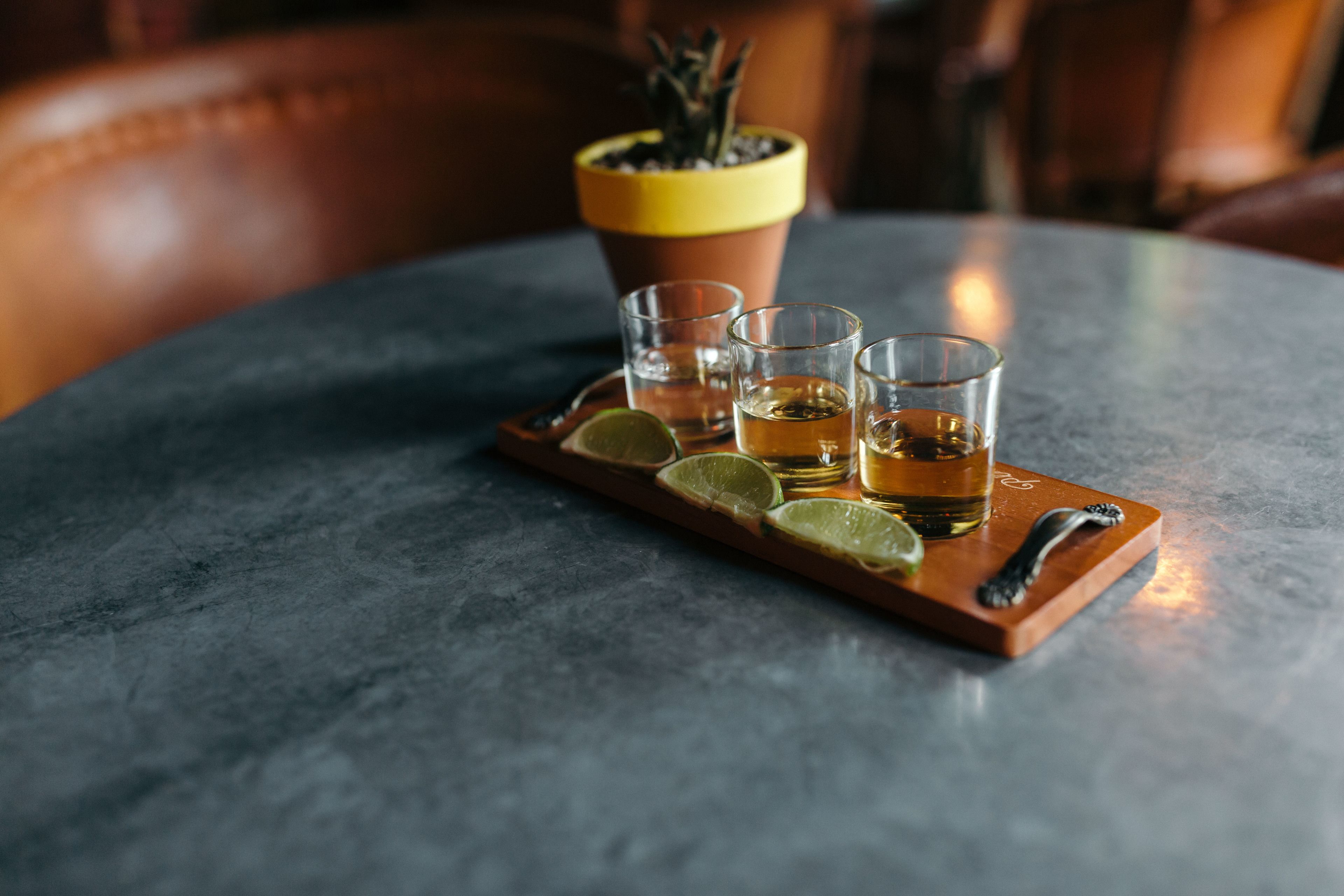 Un plateau contenant quatre verres remplis d’une boisson, des quartiers de citron vert et une cuillère décorative, posé sur une table en marbre.