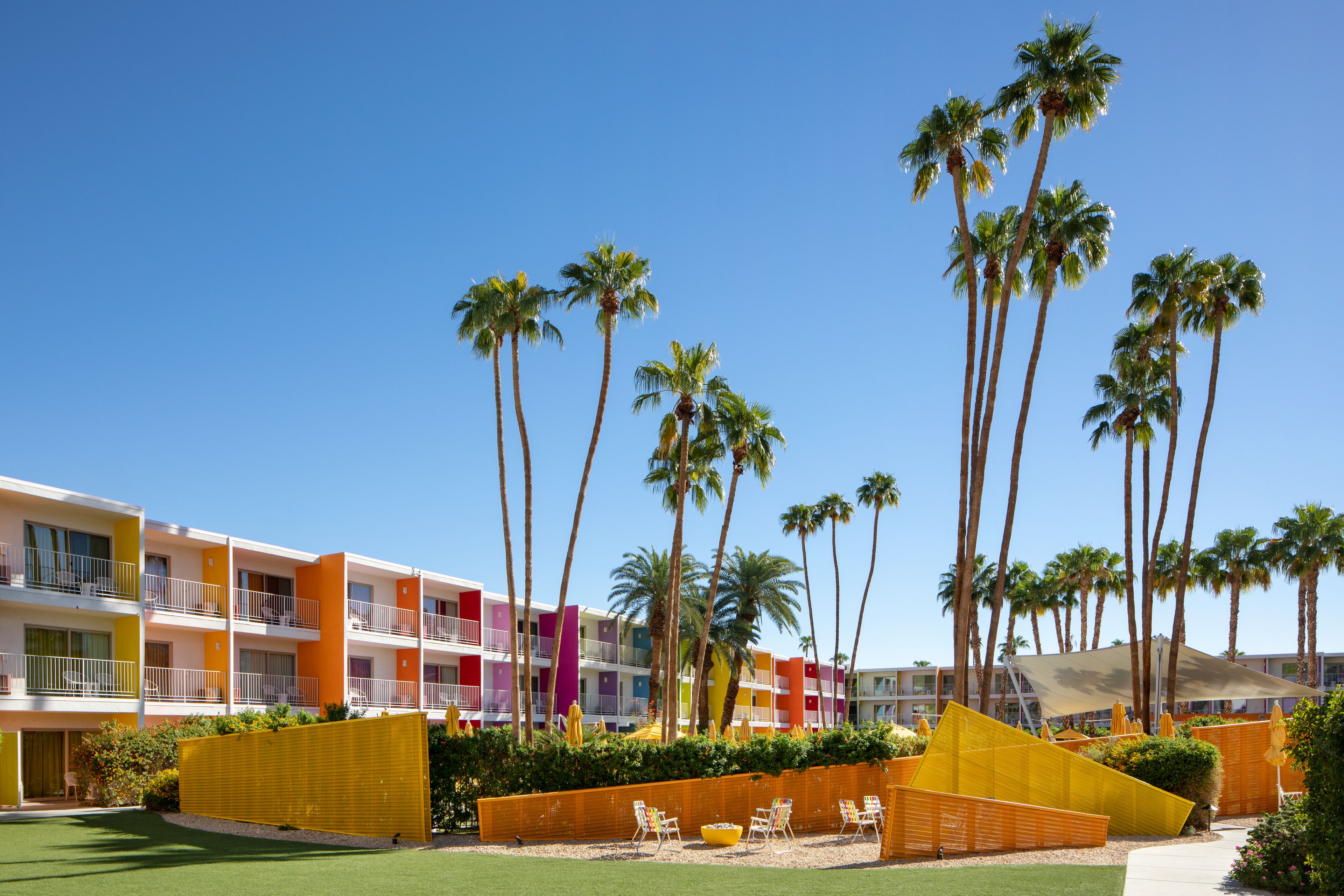 A hotel with multiple floors, balconies, and a pool area with sun loungers.
