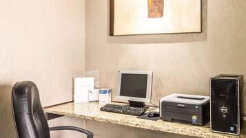 A hotel reception desk with a desktop computer, a printer, and a chair.