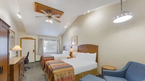 A hotel room with a large bed, two bedside tables, a desk, a chair, a ceiling fan, and a hanging light fixture. - Best Western Kokopelli Lodge (Clayton)