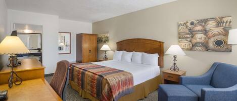 A hotel room with a bed, a desk, a chair, a couch, and a painting on the wall.
