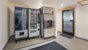 A vending machine with a selection of snacks and drinks, a stainless steel refrigerator, and a door with a frosted glass panel. - Best Western Kokopelli Lodge (Clayton)