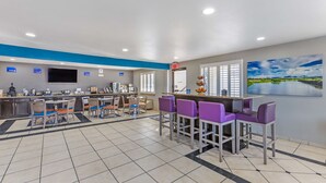 A modern hotel lobby with a bar area, seating, a television, and a painting of a landscape. - Best Western Sunland Park Inn (El Paso)