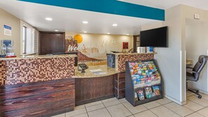A reception area with a counter, a welcome sign, a television, and a magazine rack. - Best Western Sunland Park Inn (El Paso)
