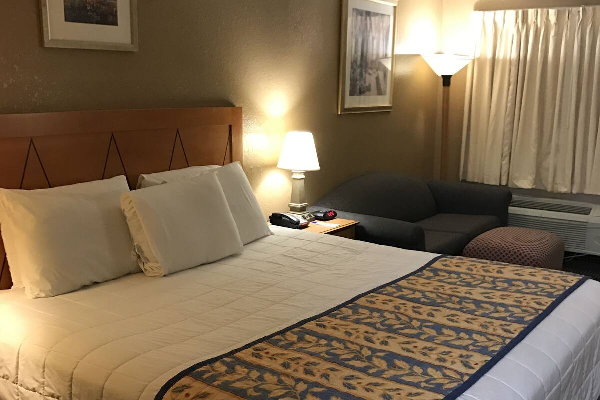 Ein Hotelzimmer mit einem großen Bett, einem Schreibtisch, einem Stuhl und einer Lampe.