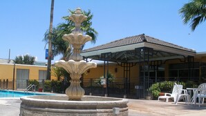 A stone fountain with a tiered design, a pool, and outdoor seating. - Americas Best Value Inn Laredo (Laredo)