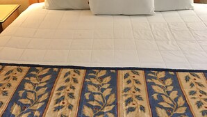 A neatly made bed with white bedding and a floral-patterned bedspread. - Americas Best Value Inn Laredo (Laredo)