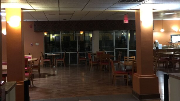 A restaurant with a tiled floor, wooden tables and chairs, and string lights. - Americas Best Value Inn Laredo (Laredo)