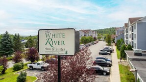 Naamplaatje voor The White River Inn & Suites, een pand van LaRkin Realty, met uitzicht op een parkeerplaats en woongebouwen.