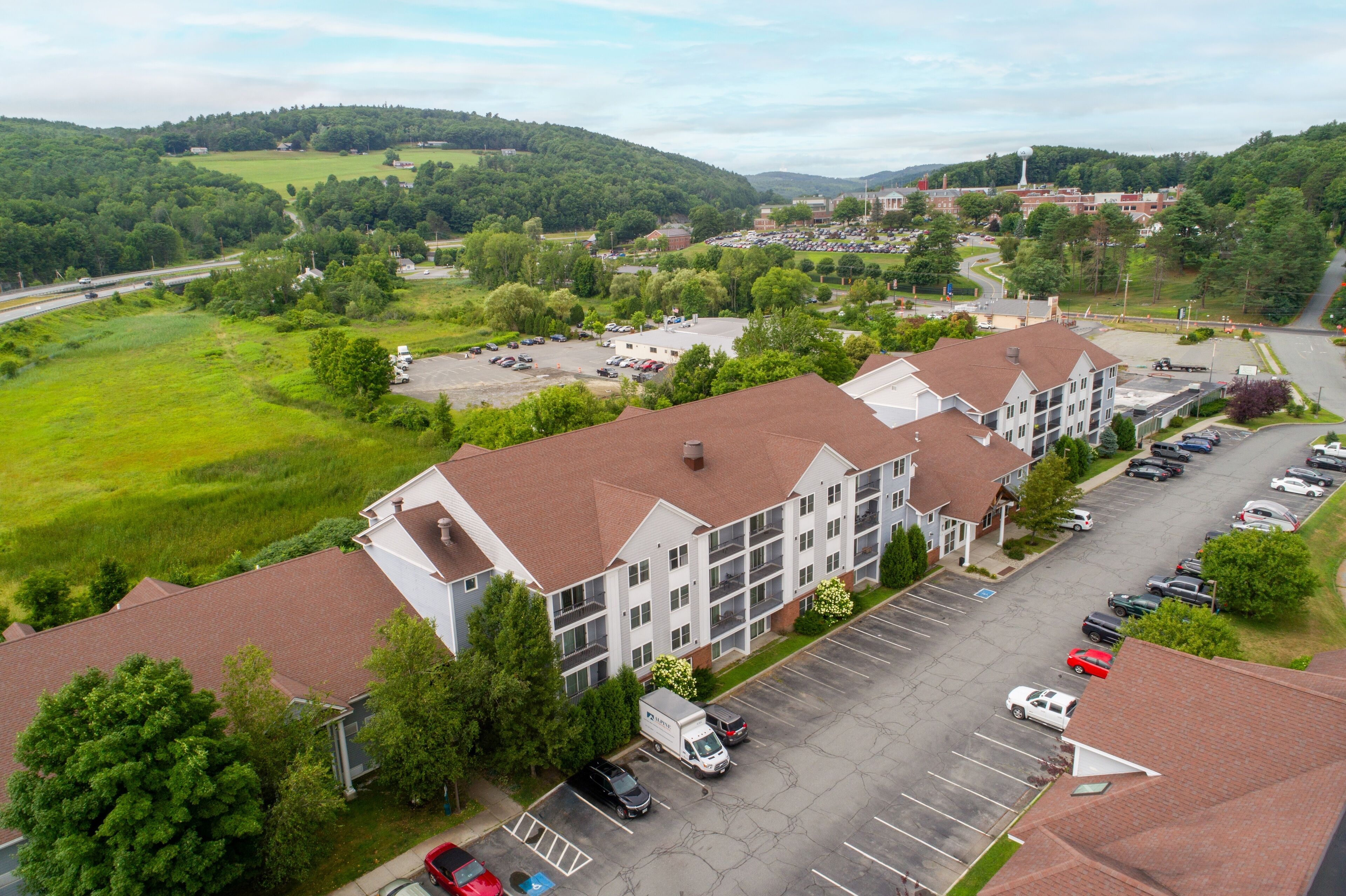 A multi-story hotel with a parking lot and a view of the surrounding landscape.
