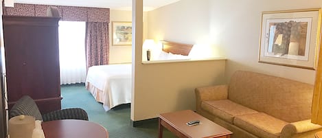 A hotel room with a bed, a sofa, a small table, and a chair.
