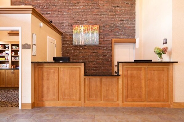 Un área de recepción con armarios de madera, pared de ladrillo y una pintura.