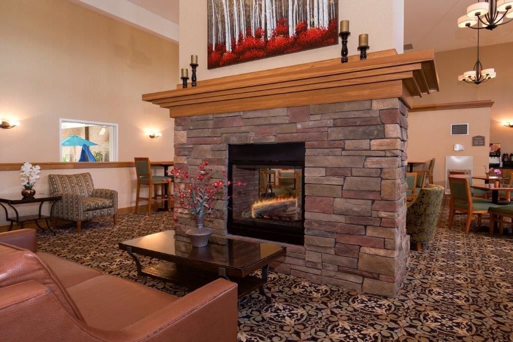Un hall acogedor con chimenea de piedra, asientos cómodos y un cuadro decorativo sobre la repisa.