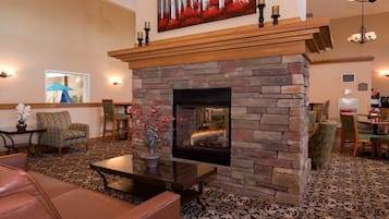 Un hall acogedor con chimenea de piedra, asientos cómodos y un cuadro decorativo sobre la repisa.