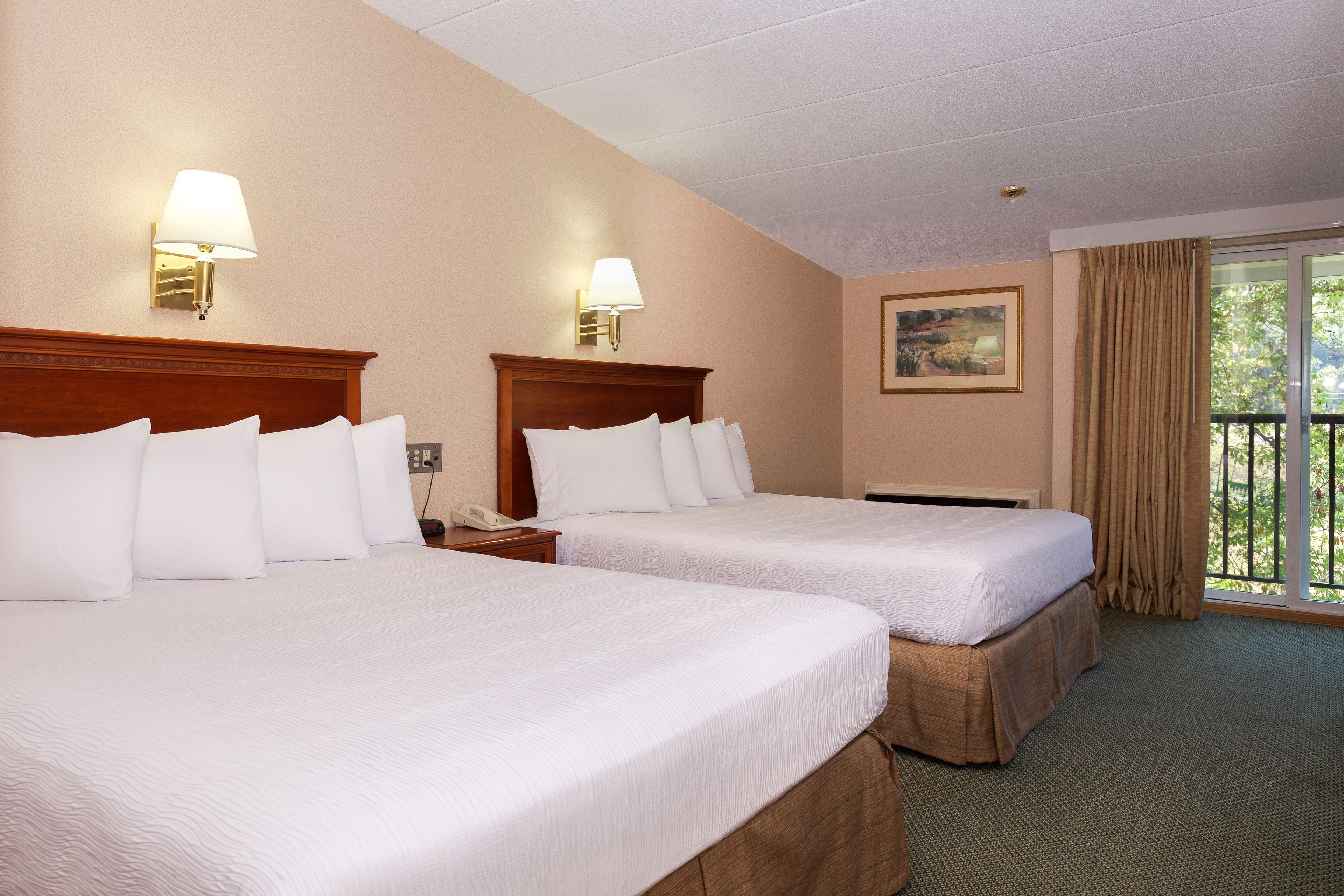A hotel room with two beds, a nightstand, a phone, a painting on the wall, and a balcony with curtains.