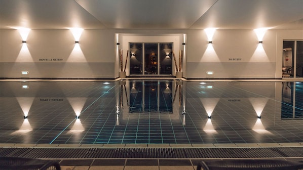 Una piscina interior con agua cristalina, rodeada de paredes con texto e iluminación.