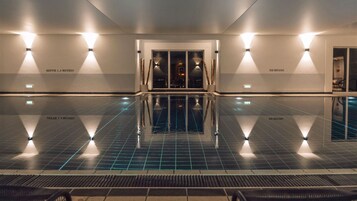 Una piscina techada, sillones reclinables de piscina