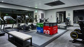 A gym with treadmills, stationary bikes, and weight machines. There is a bench and a mirror on the wall.