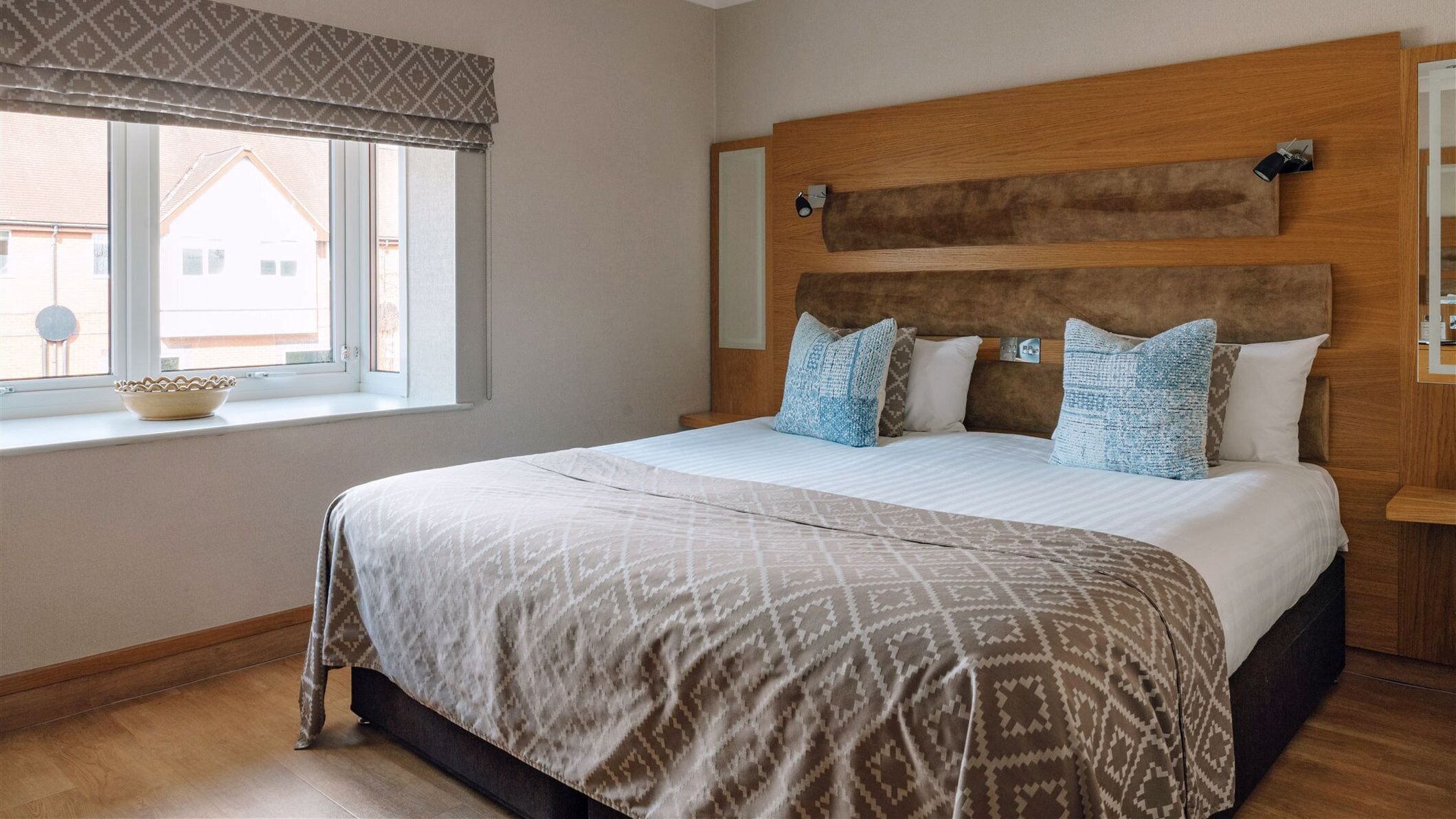 A bedroom with a large bed, a window with a view, and a wooden headboard.