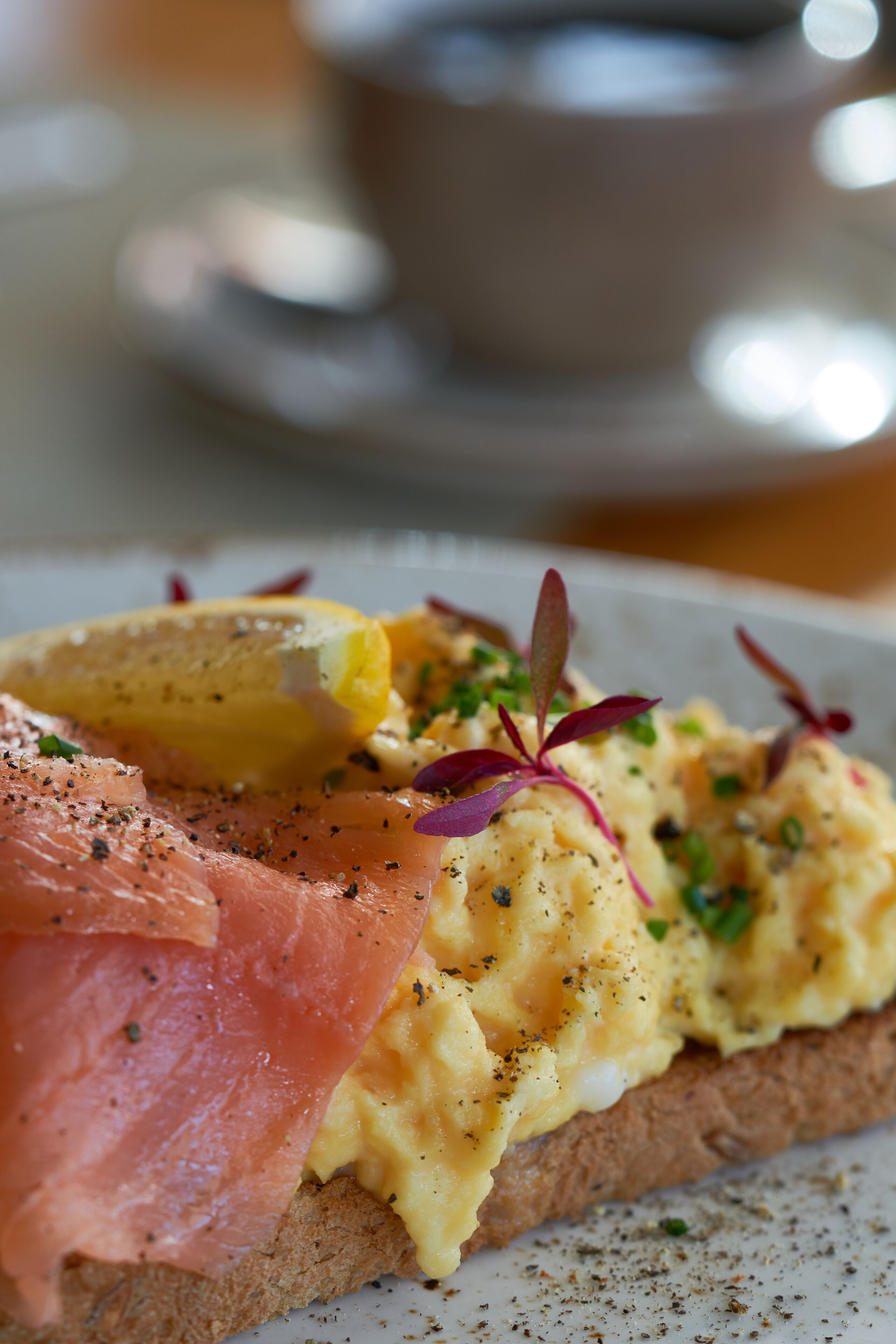 Un plato de desayuno con huevos, salmón ahumado y una rebanada de pan.