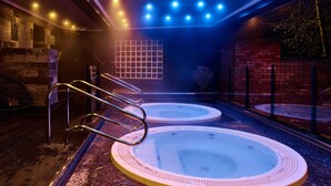 A spa area with two hot tubs, wooden flooring, and a brick wall. - Fairlawns Hotel and Spa (Walsall)
