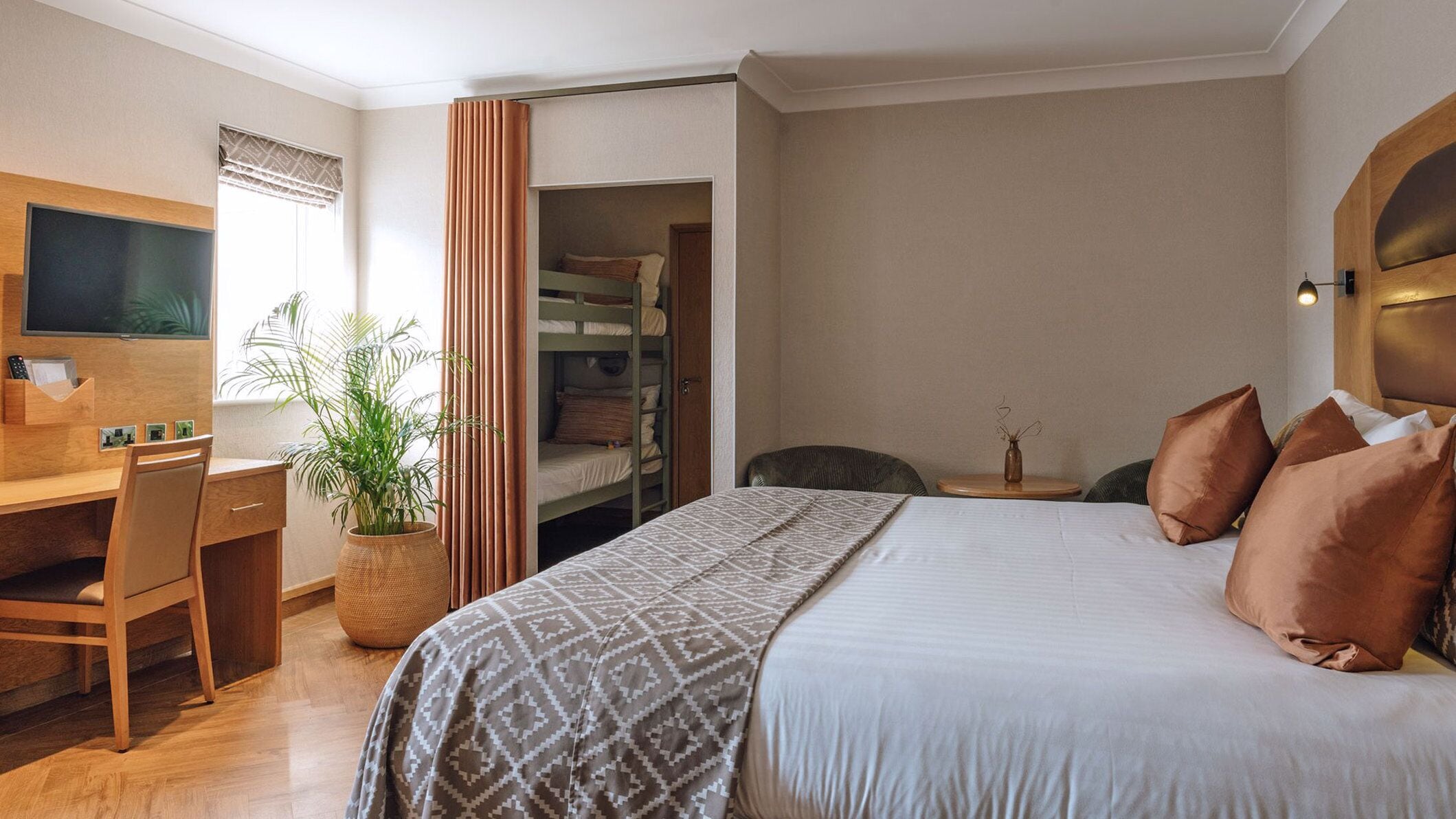 A hotel room with a bed, desk, chair, and a television.