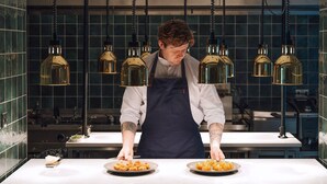 A chef in a kitchen with hanging pendant lights and a tiled backsplash. - Fairlawns Hotel and Spa (Walsall)