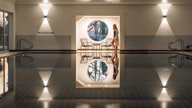 A swimming pool with a glass wall reflecting the surroundings, a 'NO LIFEGUARD' sign, and a 'Life is better at the pool' slogan. - Fairlawns Hotel and Spa (Walsall)