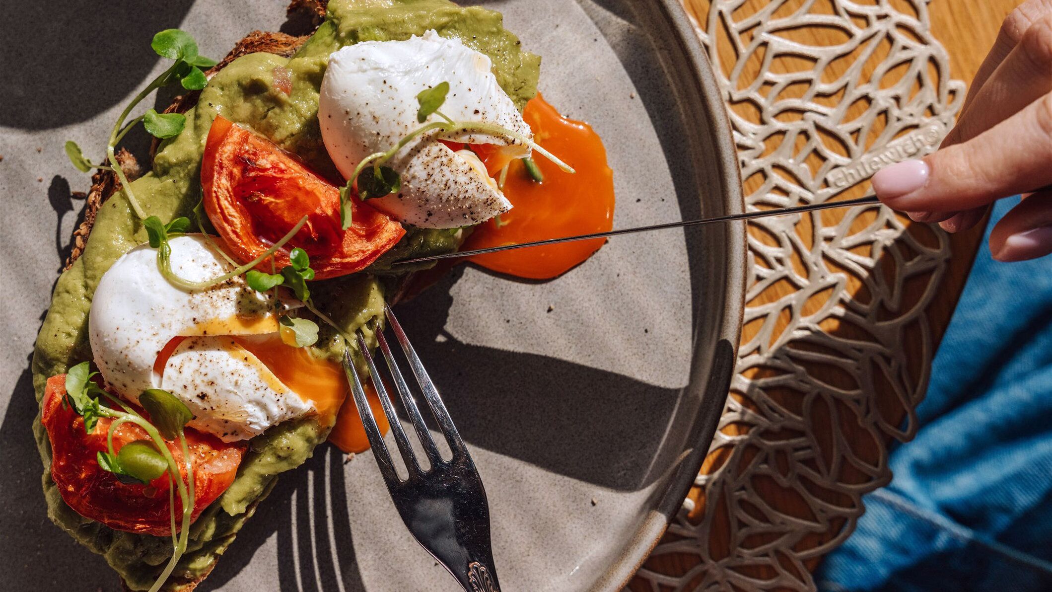 A plate of food with poached eggs, avocado, and tomatoes.
